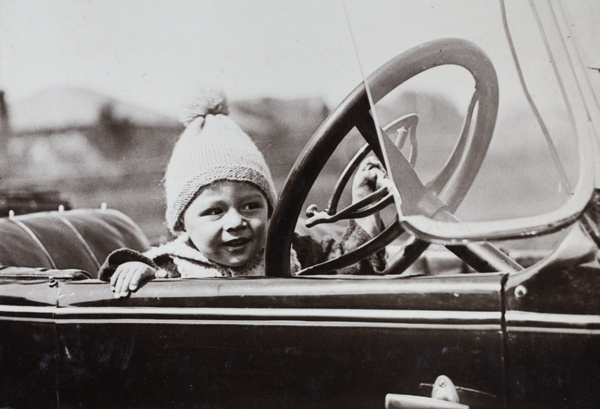 Sonny Hutchinson sitting in the driver's seat of a motorcar, Shanghai