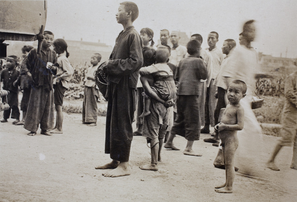Children and young people gathering to collect rice from a truck near the Huasing Road tram sheds, Shanghai, 1925