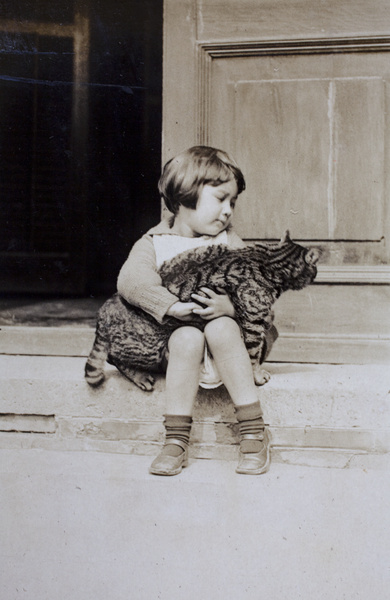 Bea Hutchinson sitting on the verandah steps and holding a cat, 35 Tongshan Road, Hongkou, Shanghai
