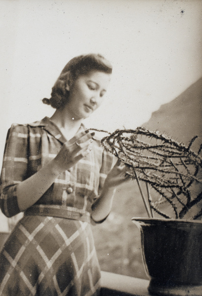 Bea Hutchinson looking at a crown of thorns cactus in the verandah of the apartment block 166-188 Prince Edward Road, Kowloon, Hong Kong