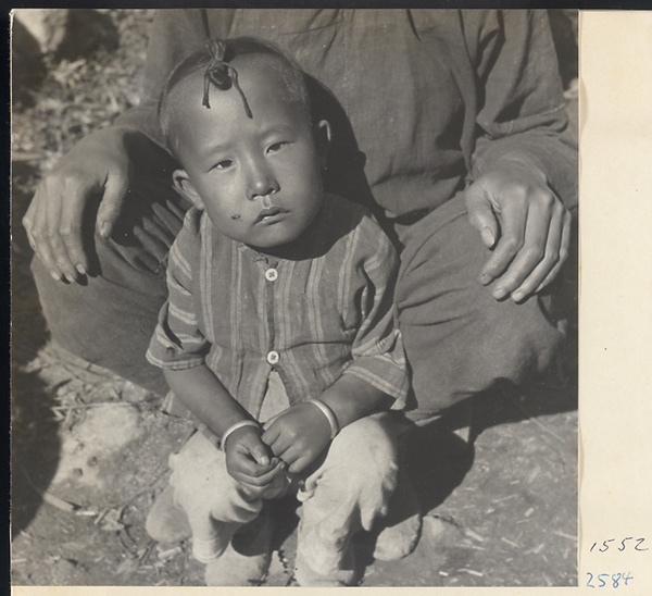 Child with topknot wearing striped shirt and bracelets