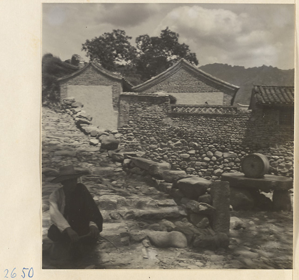 Houses, stone walls, and man sitting on steps in Sang-yuan Village [sic] in the Lost Tribe country