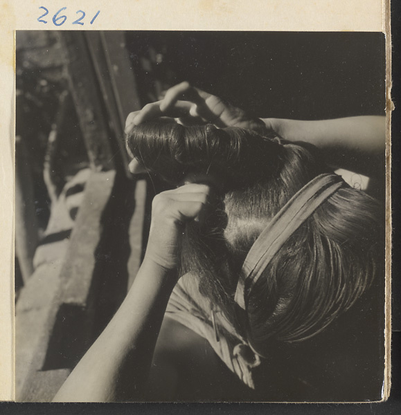 Woman doing her hair in the traditional teapot style in the Lost Tribe country