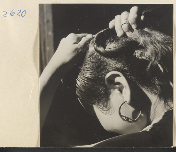 Woman doing her hair in the traditional teapot style in the Lost Tribe country