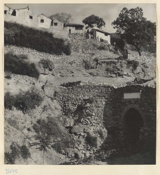 Stone bridge over dry riverbed, stone terracing, houses, and villagers in Ta-tsun Village [sic] in the Lost Tribe country