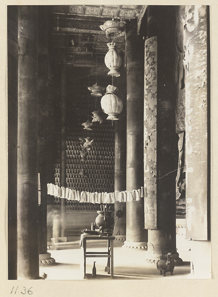 Interior view of Da cheng ge at Da Fo si showing columns, lanterns, and ritual objects