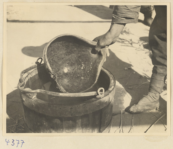 Person ladling water from a bucket with a gourd on a farm near Baoding