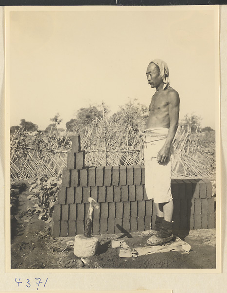 Man standing on a mold filled with clay at a brick factory near Baoding