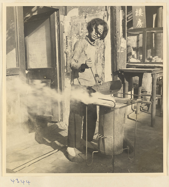 Woman tending a stove outside a shop in Baoding