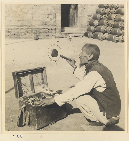 Street vendor who sells sewing thread sounding a gong called a yun luo or ling zi to attract customers in Baoding