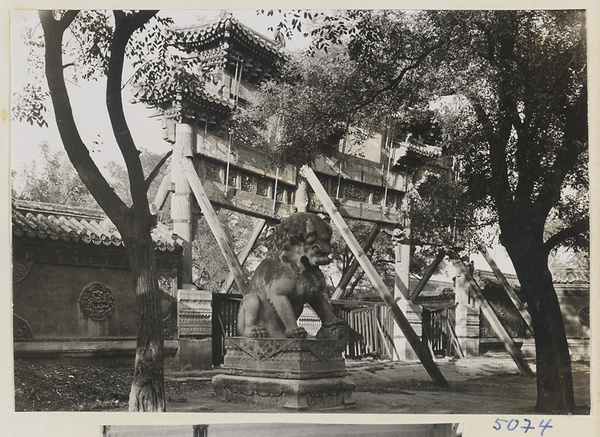 Marble lion in first courtyard and south facade of pai lou leading to second courtyard at Yong he gong