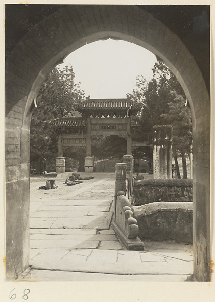 Pai lou, stone stelae, and market seen from archway of gate at Tan zhe si