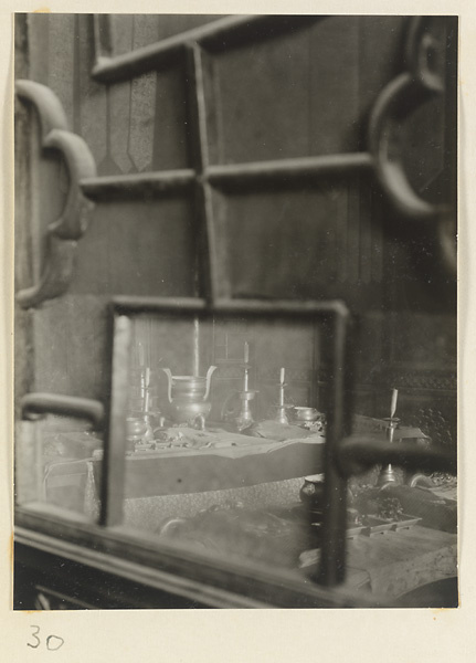 Temple interior at Xi yu si showing altar with ritual objects seen through a partition with latticework