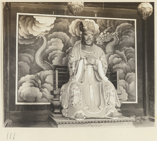 Shrine interior at Hei long tan showing a shrine figure in front of a mural with dragon and clouds