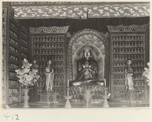 Temple interior showing statues of Buddha and attendants, ritual objects, and walls with Bodhisattva reliefs at Wan shou si