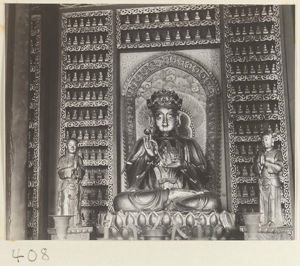 Temple interior showing niche with statues of a Bodhisattva and attendants, ritual objects, and walls with Bodhisattva reliefs at Wan shou si