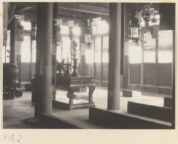 Interior of a temple building showing an altar with ritual objects, lanterns, muyu, and benches at Fa yuan si