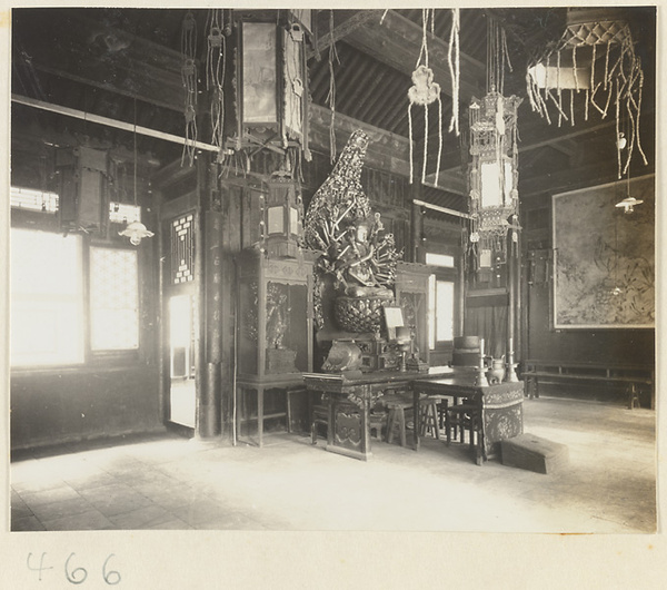 Temple interior showing altar with multi-armed Bodhisattva, ritual objects, musical instruments, lanterns, and painting at Fa yuan si