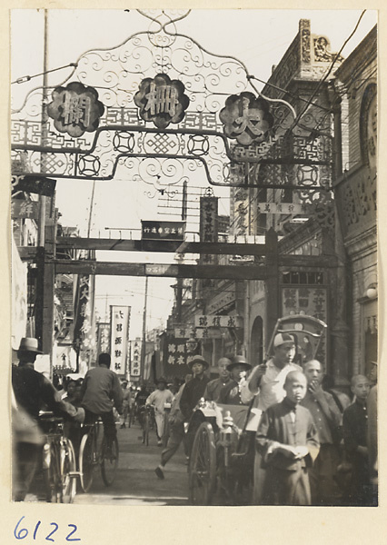 Western end of Dashalan Street showing gate, shop signs, rickshaw puller, and pedestrians