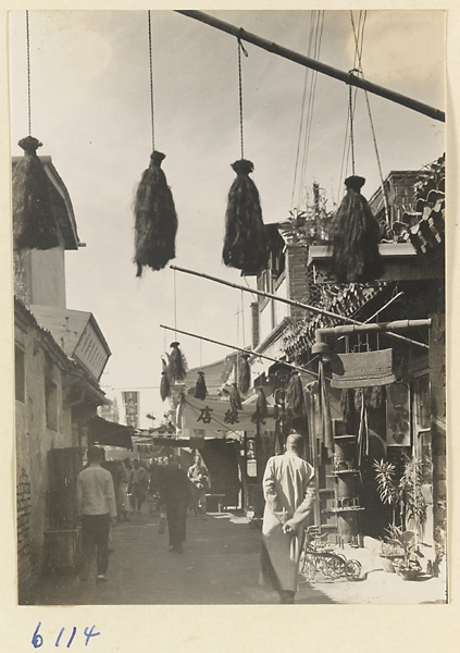 Street scene showing shop signs for a hemp-worker's shop (top), a tobacco pipe shop (right), and a tricycle