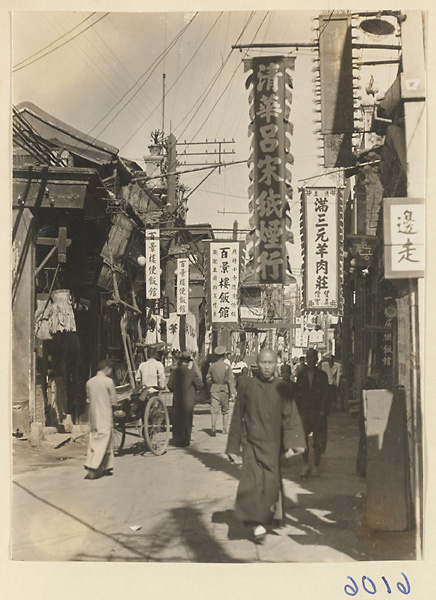 Street scene showing rickshaw puller and shop signs for a noodle shop (left), restaurants (center bottom), and a cigarette shop (center top)