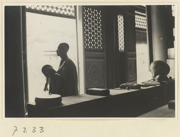 Monk playing the cymbals next to a table with a handchime, a gong, and a mu yu at Jie tai si