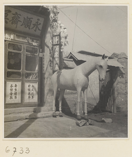 Facade of a shop that sells funeral paraphernalia showing shop signs and a paper horse