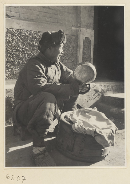 Candy vendor with box of equipment playing metal gong called a tang luo to attract a crowd