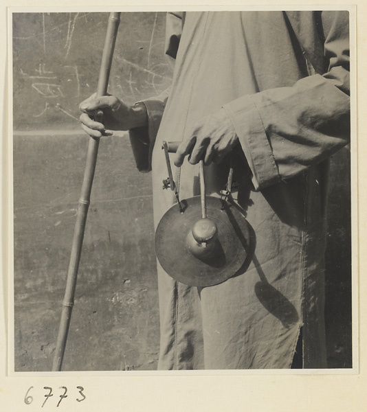 Blind fortune teller with staff and hand gong called tong dian or dian zi