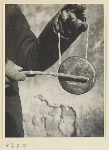 Itinerant peddlar striking a gong called a tong luo