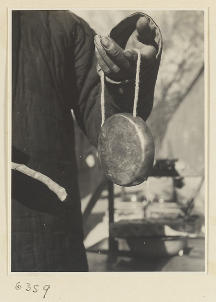 Itinerant peddlar striking a gong called a tong luo