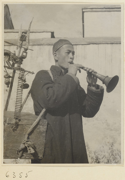 Street entertainer playing a brass instrument called a nie dou jiang or suo na to attract audience for performing mice show