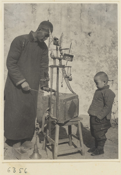 Street entertainer with a brass instrument called a nie dou jiang or suo na and boy watching performing mice show