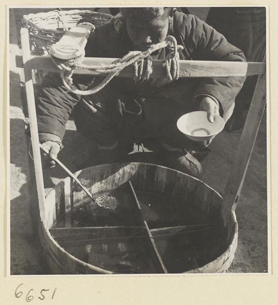 Vendor ladling goldfish from a bucket