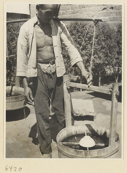 Vendor carrying buckets of goldfish on a shoulder pole