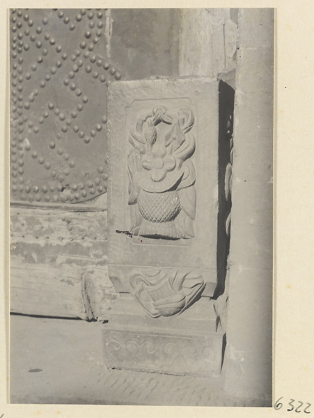 Carved door stone with floral motif and door studded with bosses in swastika pattern in background
