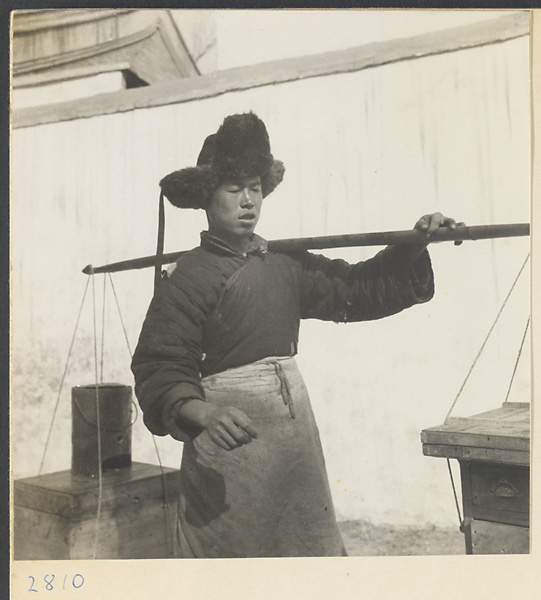 Tracery candy vendor carrying his equipment on a shoulder pole