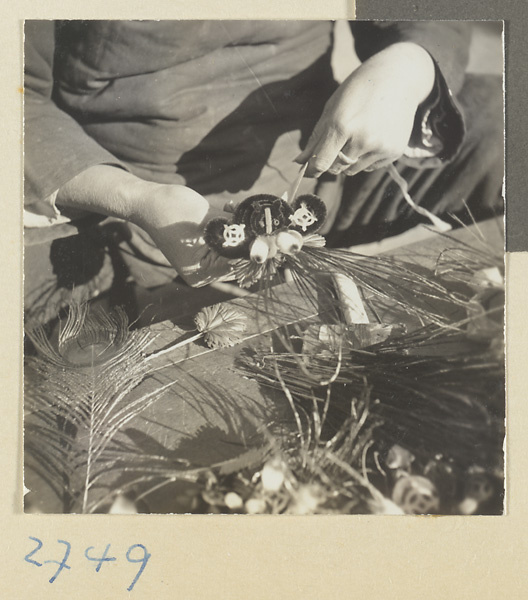 Woman tying peacock feathers to a chenille souvenir