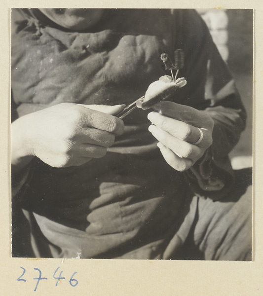 Woman shaping a chenille souvenir with tweezers