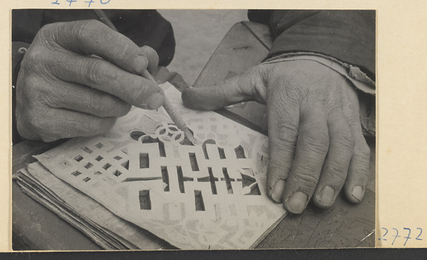 Paper-cut maker cutting through soot pattern with a knife