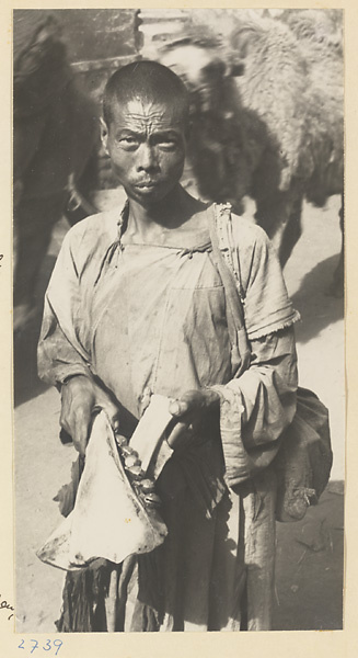 Street entertainer holding a musical instrument made of cow bone and bells