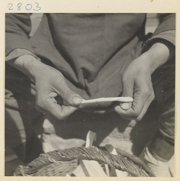 Woman wrapping twisted husks around her thumb to make a maize straw cushion