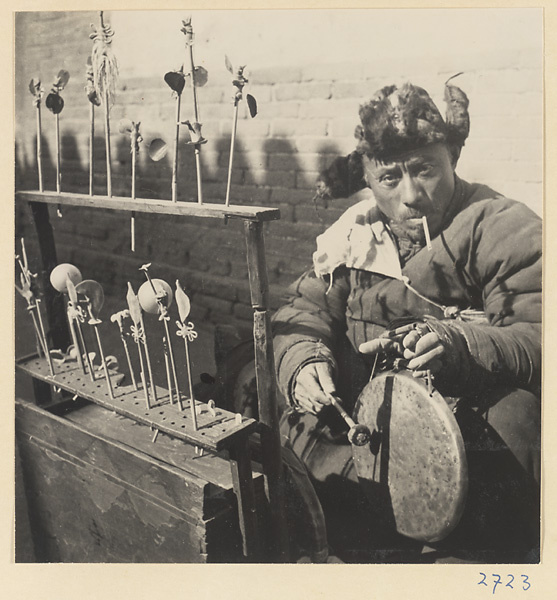 Candy vendor with display of molded candy forms striking a gong called a luo or qiu tang ren di to attract customers