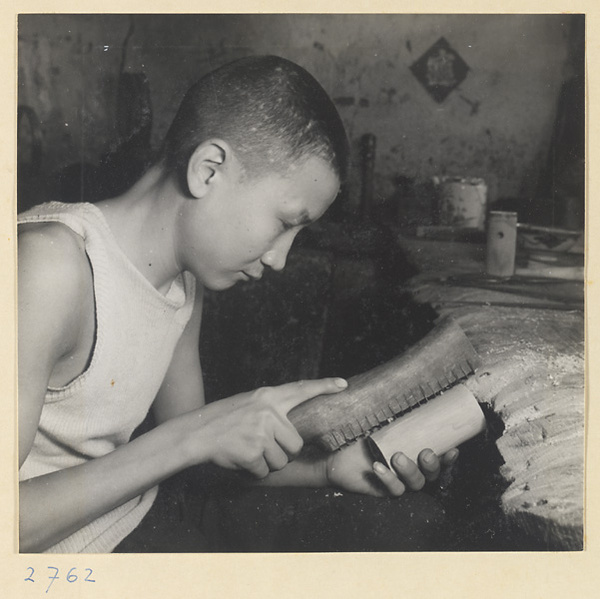 Man hand-planing the wooden body of a stringed instrument in a workshop