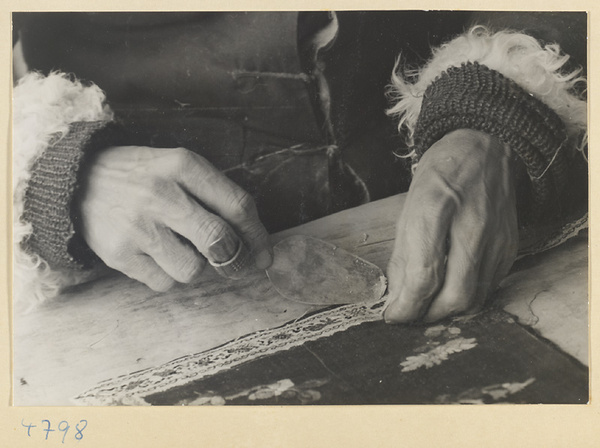 Man applying a border to a piece of silk embroidery