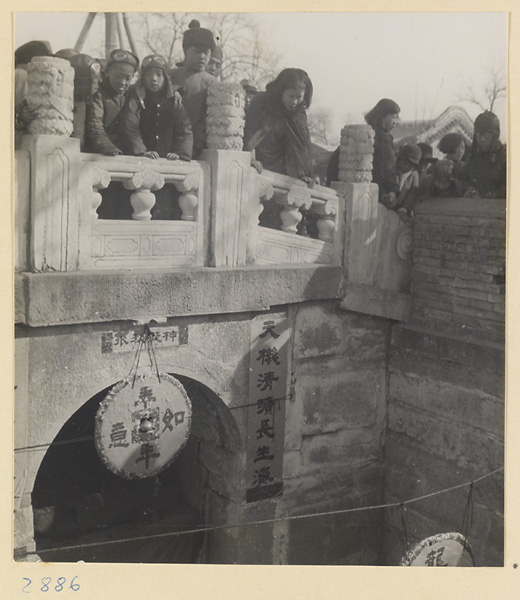 Large wooden representation of an old Chinese coin suspended from a bridge in Bai yun guan courtyard at New Year's