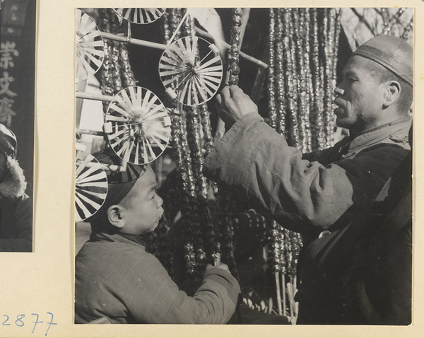 Street vendor selling pinwheels and strings of candied fruit called tang hu lu at New Year's