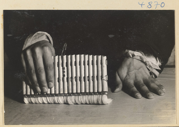 Man in a scroll-mounting shop moistening the back of a scroll painting with water using a brush called a shui shua