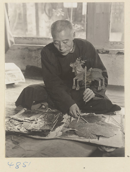 Puppeteer seated with shadow puppets