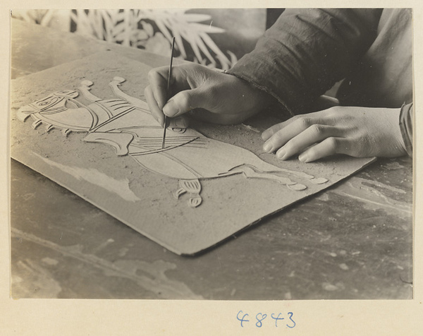 Man cutting a figure of a horse to use for a wallpaper pattern